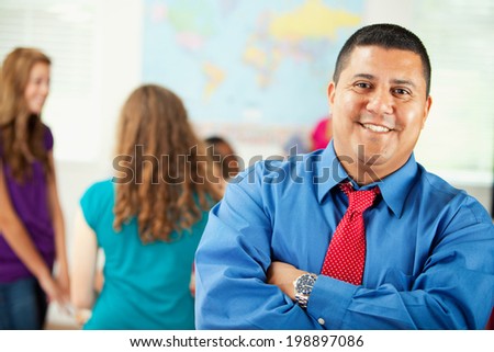 Classroom: Smiling Hispanic Teacher With Arms Crossed