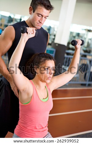 Gym: Trainer Assists Woman With Workout