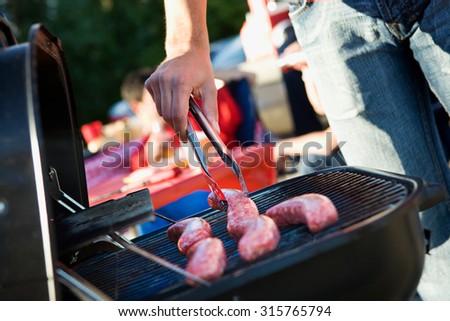 Tailgating: Man Grilling Sausages On Charcoal Grill For Party