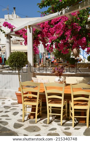 Cozy restaurant under flowering trees  in the street of Chora in Mykonos, Cyclades Island. Greece.