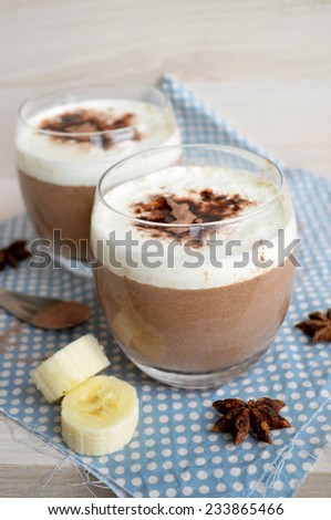 Traditional Italian dessert Panna cotta, with the addition of banana, vanilla, chocolate, cream and cocoa on wooden texture