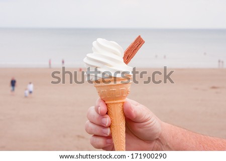 Ice- cream cone with  soft ice cream and chocolate flake with ocean as backdrop