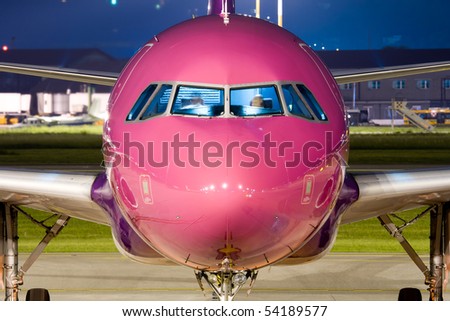 Close up of the nose of a violet airbus parked at night.