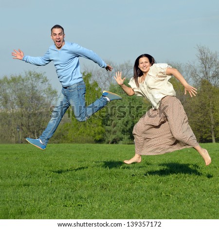 Happy girl and guy jumping high in a beautiful park.