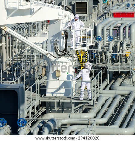 Workers on gas tankers, natural gas storage in the background. Refinery, oil and natural gas. Industrial