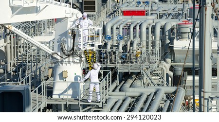 Workers on gas tankers, natural gas storage in the background. Refinery, oil and natural gas. Industrial