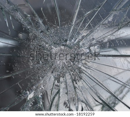 Bullet hole in shattered glass pane