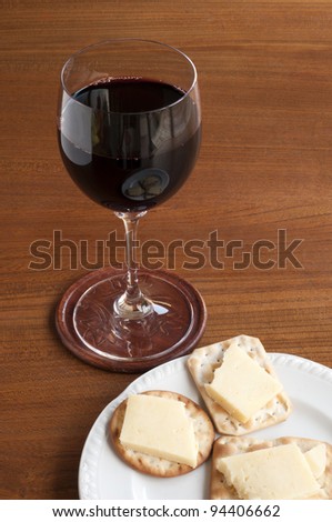 Glass of red wine accompanied by cheese and crackers