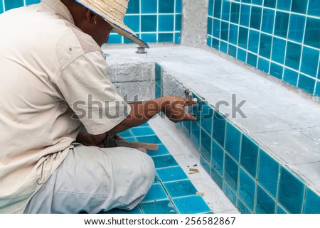 Bangkok - Thailand at Maruay Garden Hotel tile worker in tiling the pool with equipment. Man is tiling the swimming pool January 1, 2012 at Bangkok Thailand