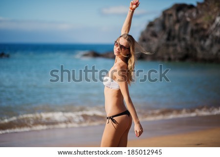 Happy relaxed woman breathing deep fresh air and raising arms on the beach with the horizon in the background