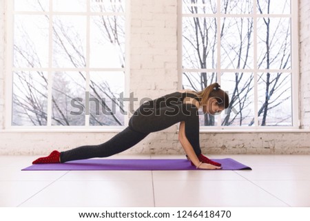 Woman practicing yoga, doing stratching  legs yoga pose on the floor of light room on yoga mat indoors. Warm up, workout