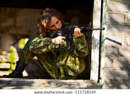A young woman with a rifle on maneuvers