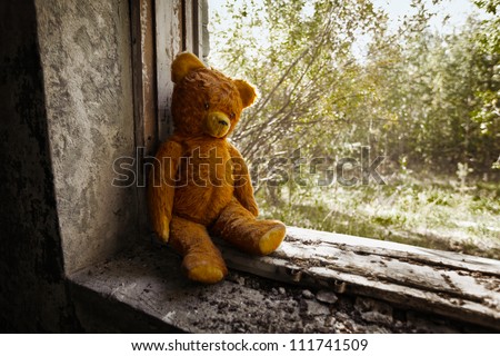 Sad child doll - old toy bear in the ruins. Neglect concept.