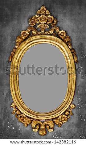 Old-fashioned oval gilt frame for a mirror on a gray concrete wall