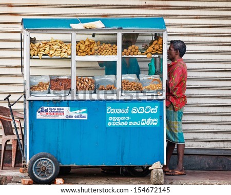 BENTOTA, SRI LANKA - APR 27: Man buys food in small portable street shops on Apr 27, 2013 in Bentota, Sri Lanka. Mobile street food sellers are popular in Sri Lanka.