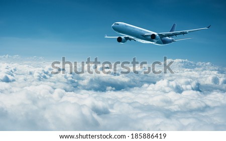 Passenger jet plane flies above the clouds - international travel with modern airlines
