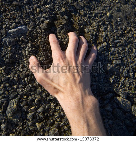Man\'s hand clinging stony ground