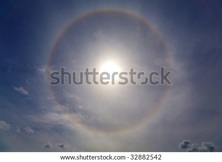 Circles halo in the blue cloudy sky around of the sun
