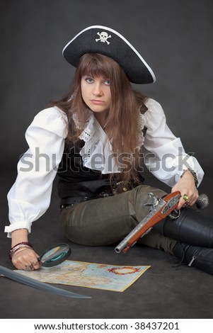 The woman in costume of the pirate with a sea map and a magnifier glass