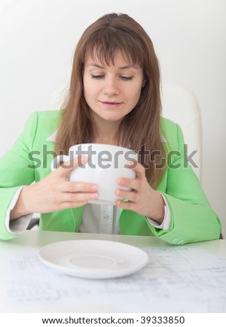 The woman looks in a huge cup for coffee