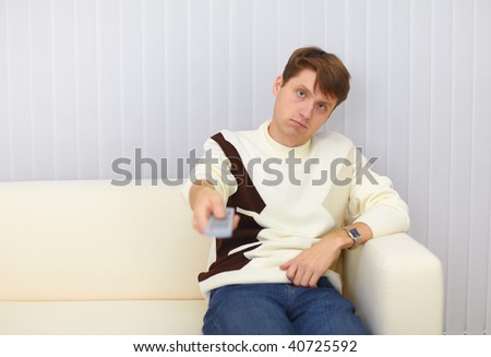 The guy sits on a sofa and watches TV