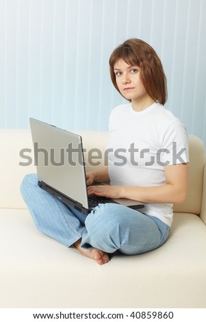 The young girl with the laptop sits on a sofa