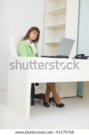Businesswoman sits at a table at light office with the laptop