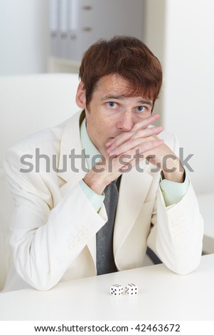 The young businessman in a white suit sits at a table