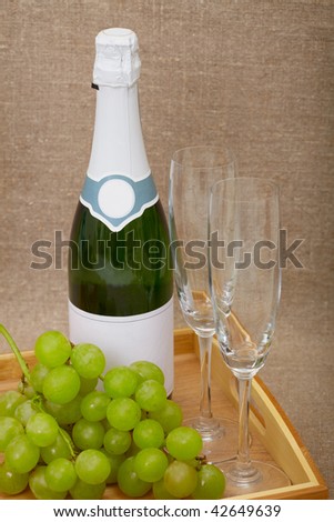 Bottle of sparkling wine with grapes and wine glasses