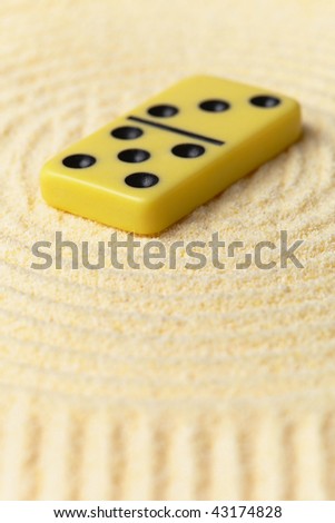 Domino on a surface of yellow sand - an art miniature