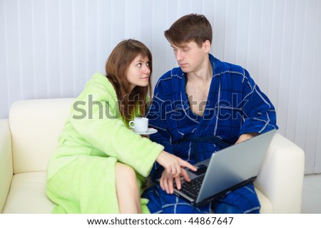 The man learns the girlfriend to work in the Internet sitting on a sofa