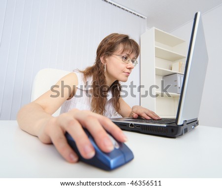 The amusing woman attentively studies the Internet by means of the laptop