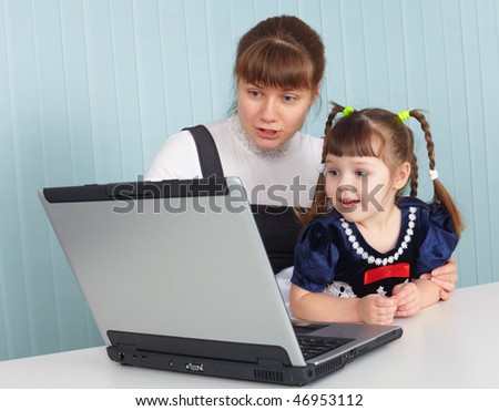 Young mother teaches daughter to use a computer