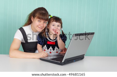 Mom and daughter happily playing with laptop