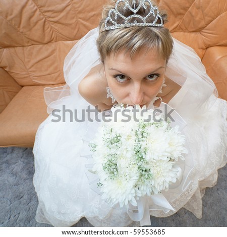The amusing bride sits on a sofa with a bouquet - the top view