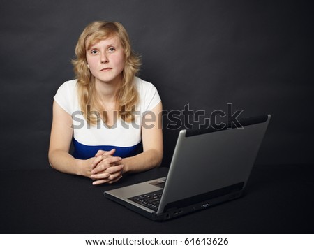 The young woman sits at a table with the computer