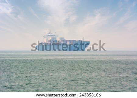 Large, fully-loaded, commercial container ship at anchor, just off the coast.