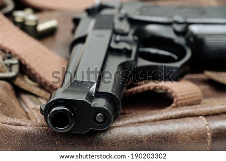 Semi-automatic handgun lying over a Leather handbag, 9mm pistol, Close-up Barrel.