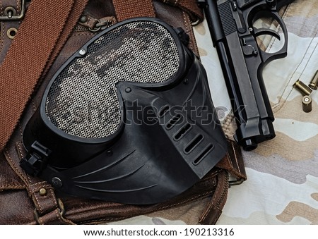 Airsoft mask, Metal Mesh Shooting Face Mask, protection mask, Black Mask safety sport gun,  lying over a Leather handbag .