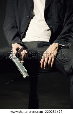 Man Holding Gun, Close up image of A Man sitting on chair holding a Gun, Image of assassin,Semi-automatic handgun, 45 pistol.