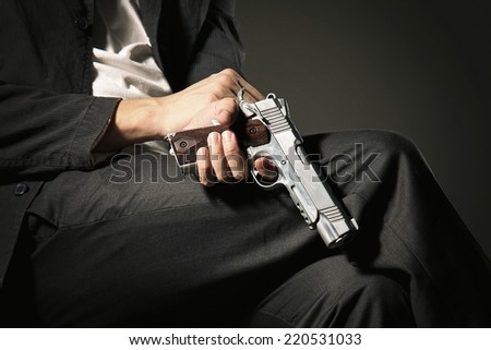 Close up image of A Man sitting on chair holding a Gun