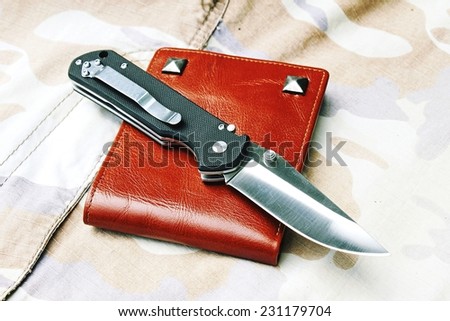 Pocket knife, Black tactical knife on military background. (Color Process)