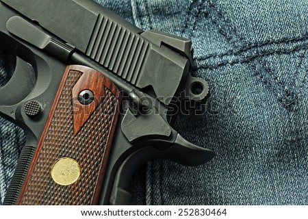 Semi-automatic handgun lying over a blue jeans, .45 pistol, Close-up cock and save.