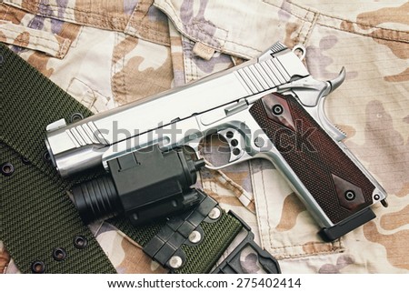 Semi-automatic handgun on camouflage background, Gun on Military texture, .45 pistol. (Color Process)