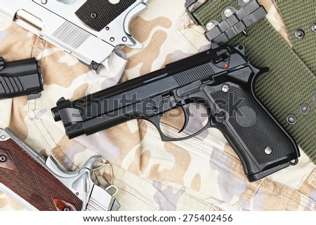 Many Guns on Military texture. Handguns on camouflage background. 9mm, 11mm Pistols.