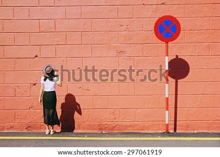 Young woman portrait with brown hat. Model posing and standing near brick wall and no parking traffic sign. Woman and traffic sign, Minimalism portrait.