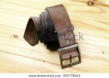 Leather belt with a buckle on a wooden board. Men fashion. Men accessories.