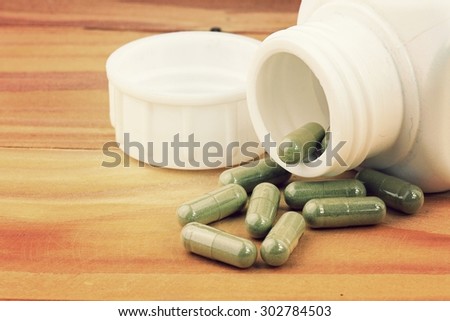 Herb capsule spilling out of a bottle, Close up image of herbal medicine. (Vintage Style Color)