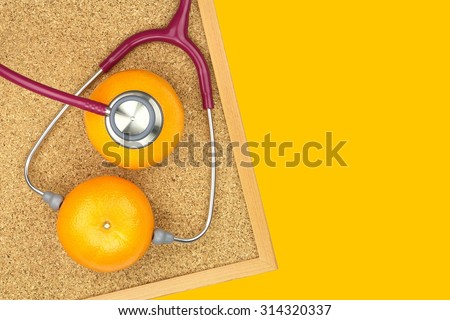 Stethoscope examining orange on a cork board. Medical equipment, Healthy food, Healthy eating concept.