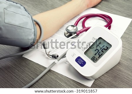 Doctor measuring blood pressure of patient, Digital Blood Pressure Monitor on wood background, Medical equipment, Examining equipment. (Vintage Style Color)